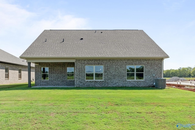 back of house featuring a yard, central AC, brick siding, and a shingled roof