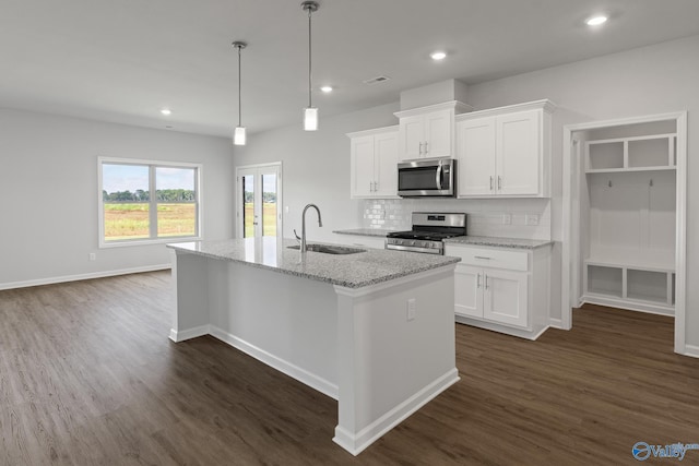 kitchen with an island with sink, visible vents, a sink, stainless steel appliances, and decorative backsplash
