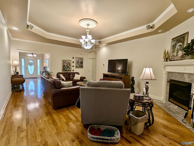 living area featuring ornamental molding, an inviting chandelier, wood finished floors, and a tray ceiling