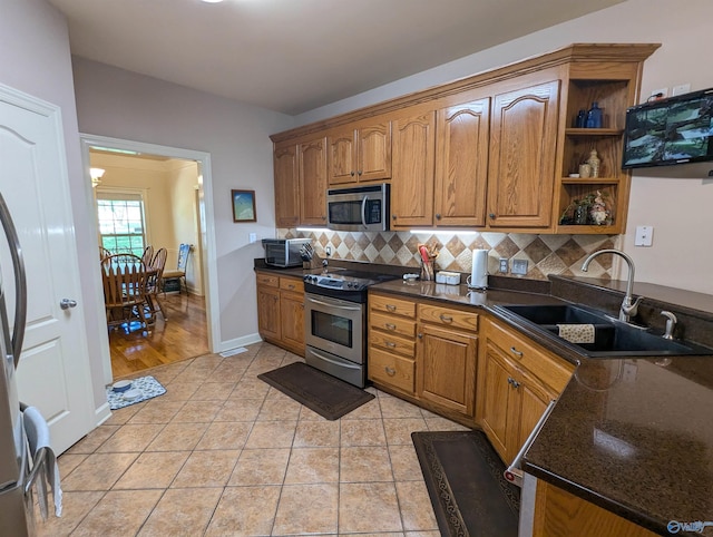 kitchen featuring light tile patterned floors, open shelves, a sink, appliances with stainless steel finishes, and backsplash
