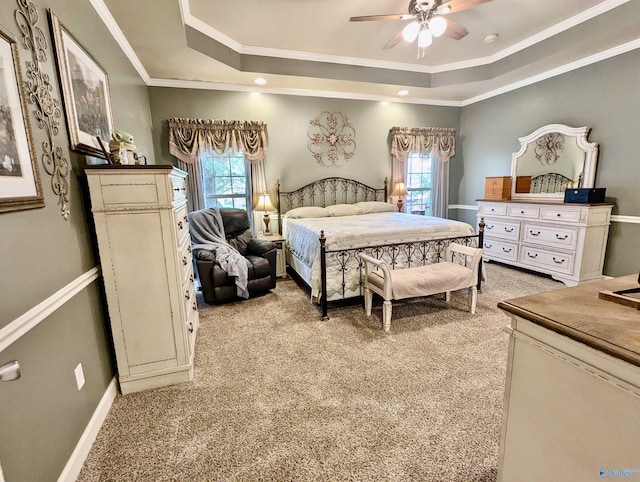 bedroom with light carpet, a tray ceiling, and multiple windows