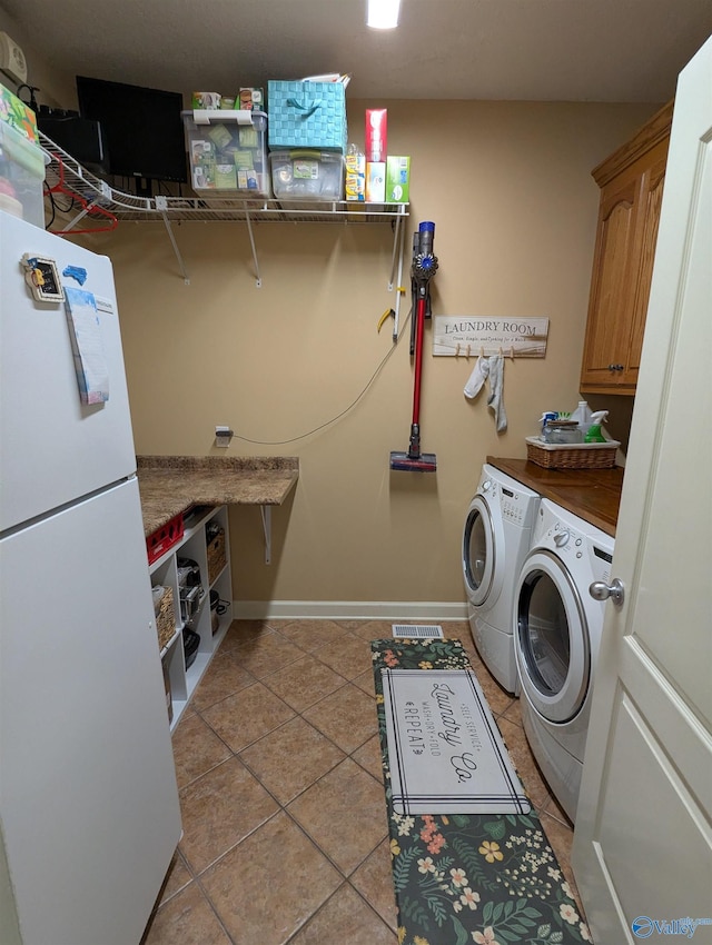 laundry area featuring cabinet space, light tile patterned flooring, separate washer and dryer, visible vents, and baseboards