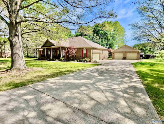 ranch-style house featuring a detached garage, a front lawn, and covered porch
