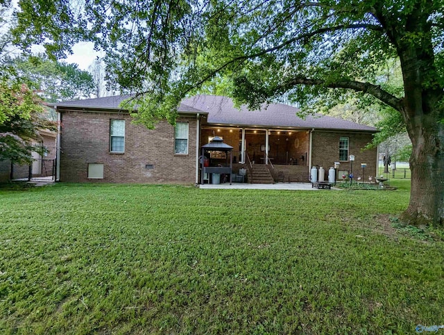 back of property featuring a lawn, roof with shingles, a patio, and brick siding