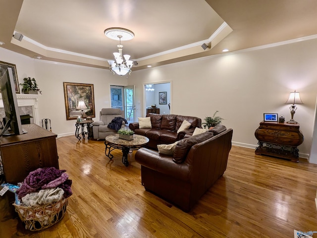 living room with wood finished floors, an inviting chandelier, crown molding, and a tray ceiling