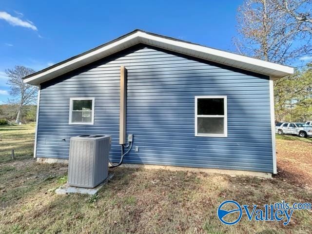 view of side of property with cooling unit and a yard