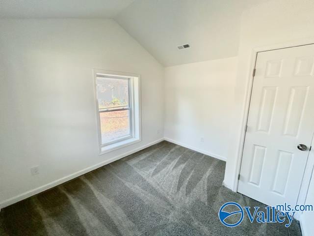 unfurnished bedroom featuring dark carpet and lofted ceiling