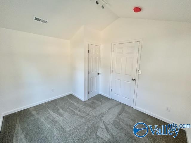 carpeted empty room featuring vaulted ceiling