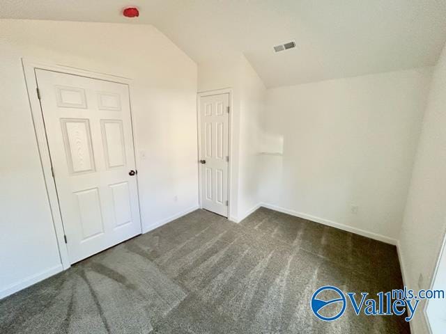 carpeted spare room with lofted ceiling