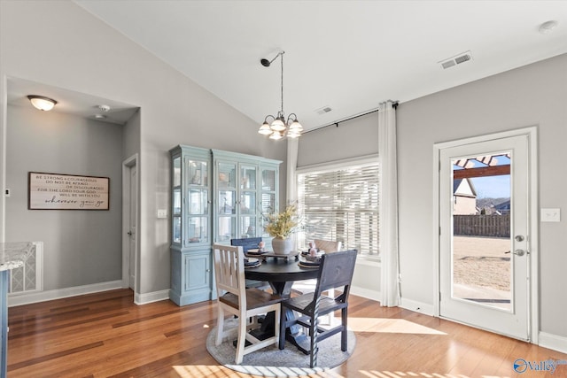 dining area featuring wood-type flooring, lofted ceiling, and a notable chandelier