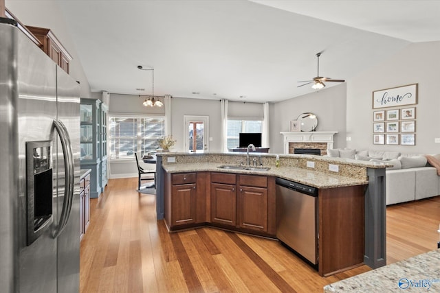 kitchen featuring sink, light stone countertops, an island with sink, and appliances with stainless steel finishes