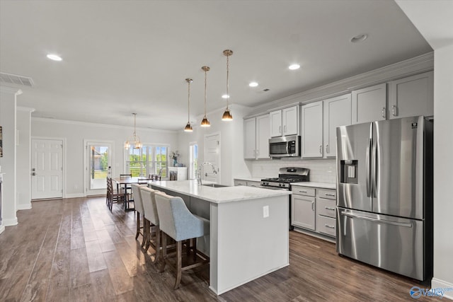 kitchen featuring pendant lighting, a center island with sink, stainless steel appliances, a kitchen bar, and dark hardwood / wood-style flooring