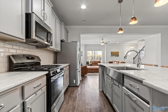 kitchen with appliances with stainless steel finishes, light stone countertops, dark hardwood / wood-style flooring, gray cabinets, and decorative light fixtures