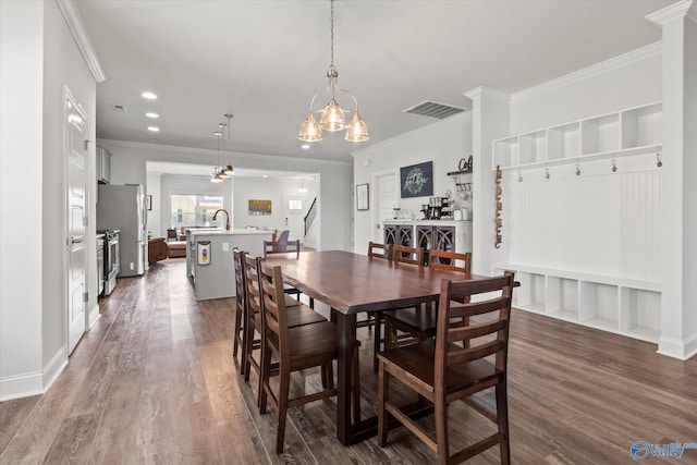 dining space with crown molding, dark wood-type flooring, and a chandelier