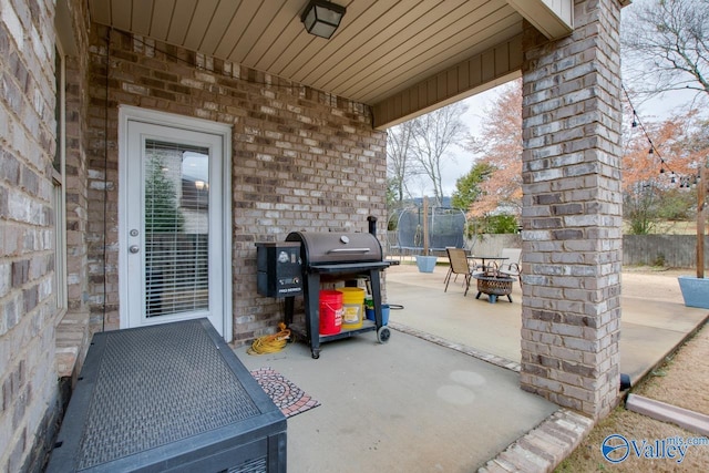 view of patio / terrace with a trampoline, a grill, and an outdoor fire pit