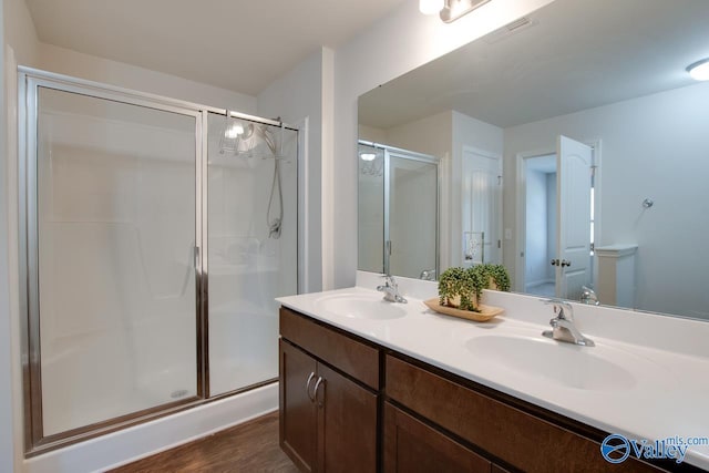 bathroom with hardwood / wood-style flooring, vanity, and a shower with shower door