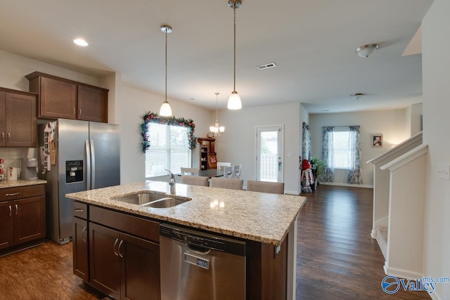 kitchen with sink, light stone counters, dark hardwood / wood-style floors, stainless steel appliances, and a kitchen island with sink