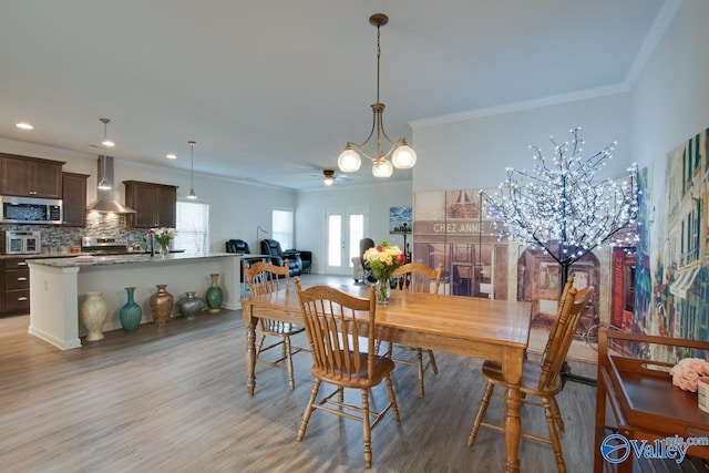 dining space featuring ceiling fan with notable chandelier, ornamental molding, light hardwood / wood-style floors, and french doors