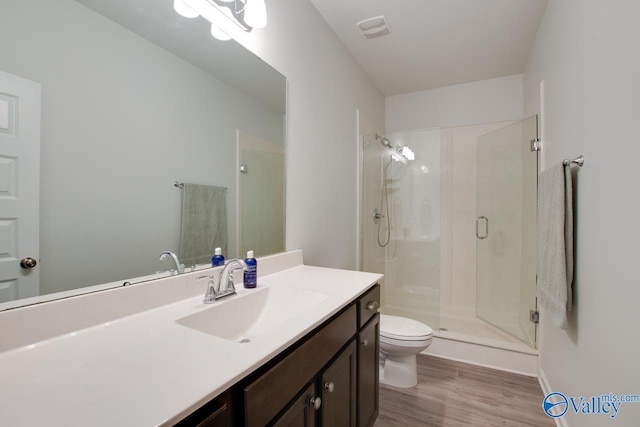 bathroom featuring toilet, walk in shower, hardwood / wood-style floors, and vanity