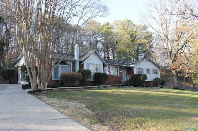 single story home featuring a front lawn, a garage, brick siding, and a chimney