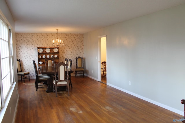 dining area featuring dark wood-type flooring and an inviting chandelier