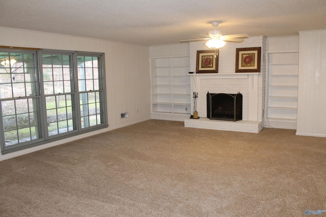 unfurnished living room featuring built in shelves, carpet, ceiling fan, a textured ceiling, and a brick fireplace