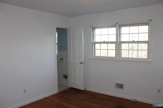 spare room featuring visible vents, baseboards, and dark wood-style floors