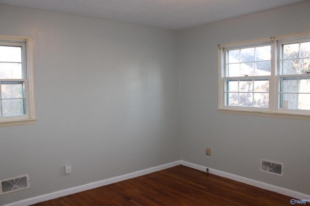 spare room featuring visible vents, dark wood-type flooring, and baseboards