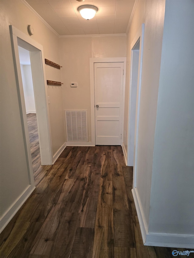 corridor featuring visible vents, baseboards, crown molding, and dark wood-type flooring