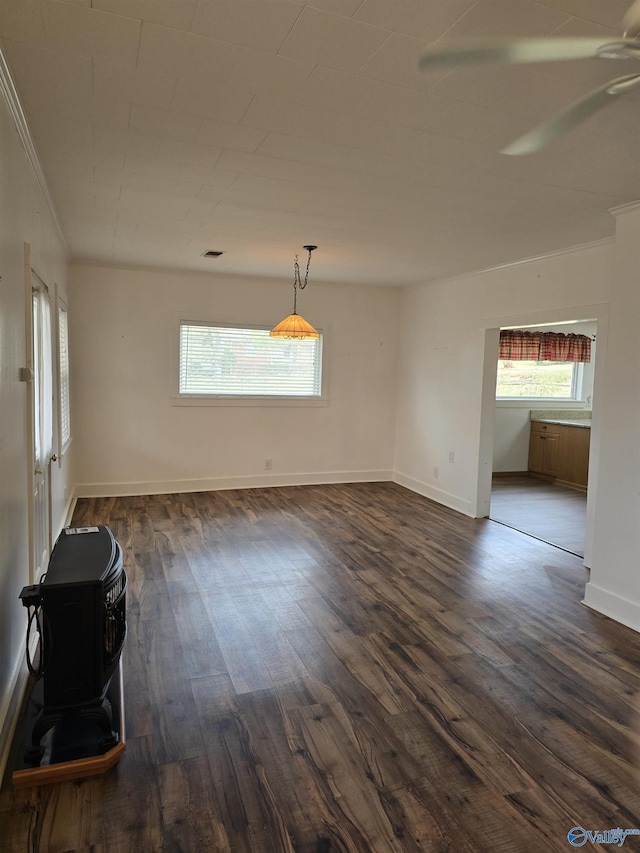 empty room featuring dark wood finished floors, visible vents, crown molding, and baseboards