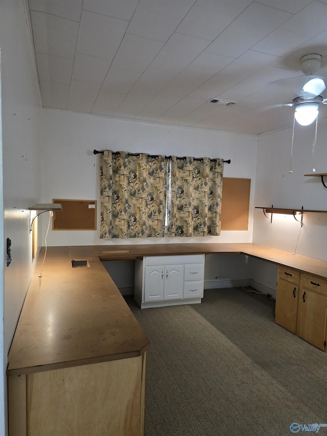 kitchen with visible vents, white cabinetry, built in study area, and a ceiling fan