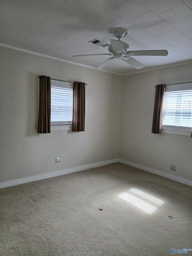 carpeted empty room with visible vents, plenty of natural light, baseboards, and ornamental molding