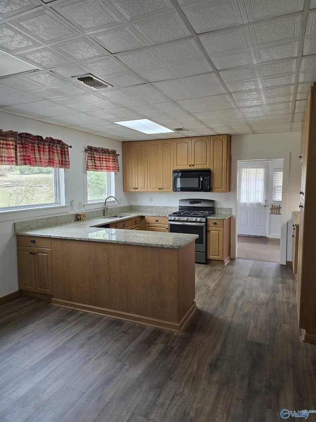 kitchen with visible vents, black microwave, dark wood finished floors, stainless steel gas range, and a sink