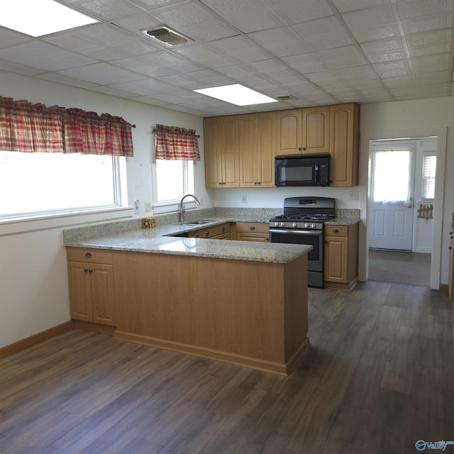 kitchen with dark wood-style floors, a peninsula, a sink, black microwave, and gas range