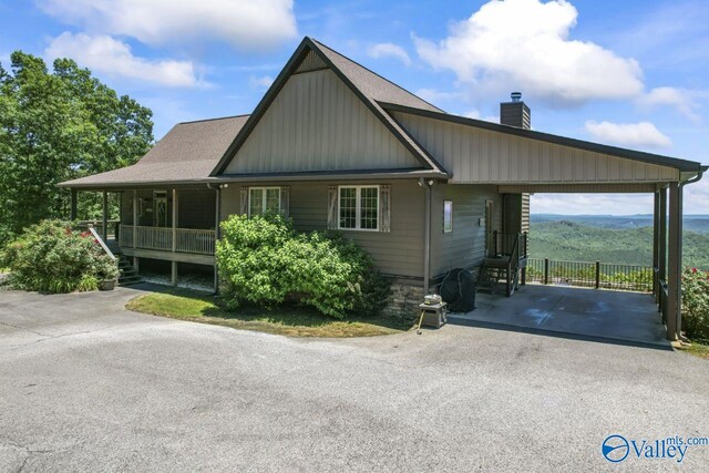 8879 County Road 27, Springville, AL 35146 - view of front of home with driveway, a chimney, a carport, board and batten siding, and covered porch