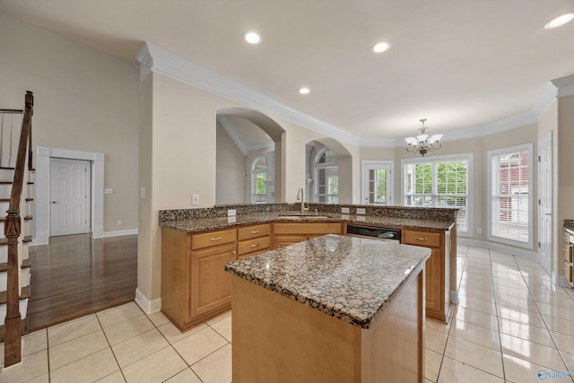kitchen featuring a sink, baseboards, light tile patterned floors, a kitchen island, and ornamental molding