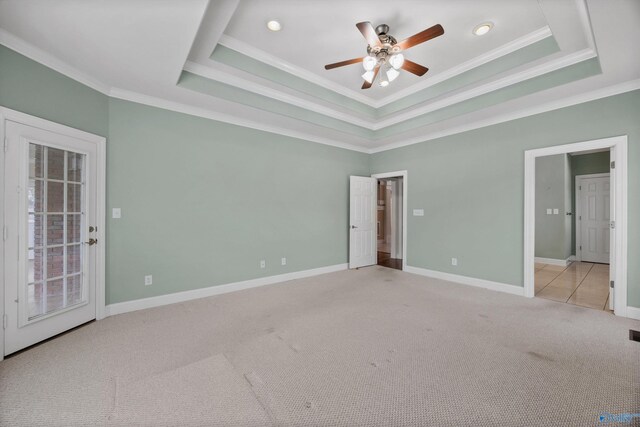 unfurnished bedroom featuring crown molding, a tray ceiling, light colored carpet, and baseboards