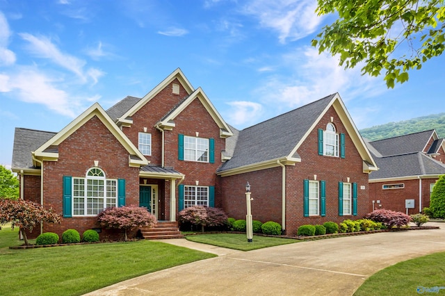 view of front of house featuring brick siding, a shingled roof, and a front lawn