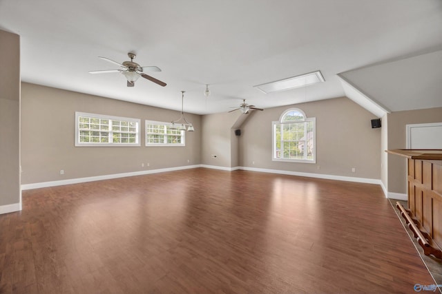 additional living space featuring plenty of natural light, dark wood finished floors, ceiling fan, and baseboards