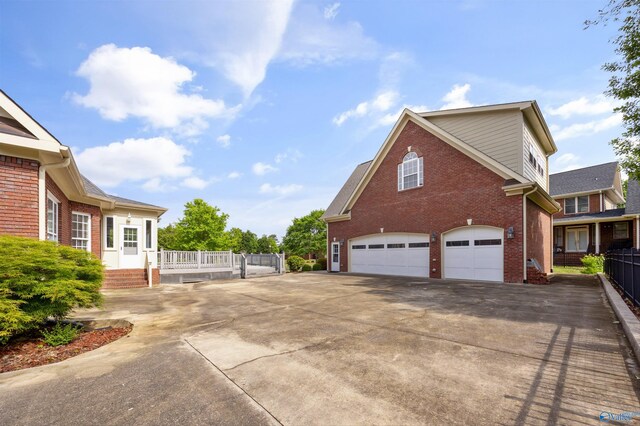 view of side of home with brick siding, a garage, fence, and driveway