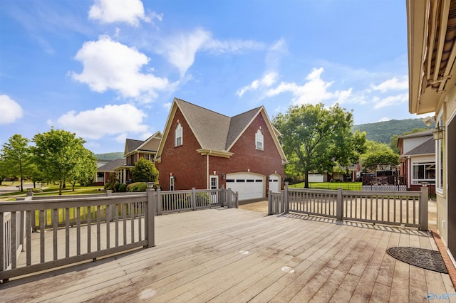 wooden deck with a mountain view, an attached garage, and concrete driveway