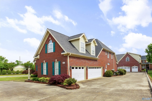traditional-style house featuring a shingled roof, an attached garage, driveway, and brick siding