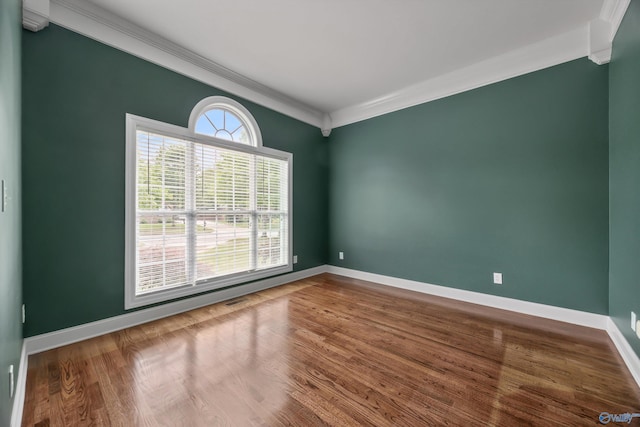 spare room with baseboards, ornamental molding, and wood finished floors
