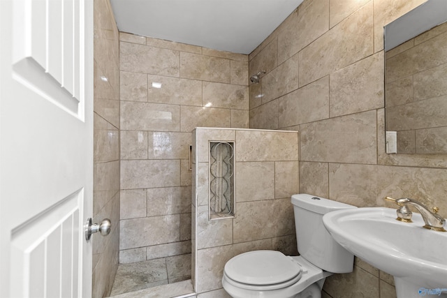 full bathroom featuring tile walls, a sink, toilet, and tiled shower