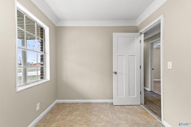 unfurnished room featuring light tile patterned floors, ornamental molding, and baseboards