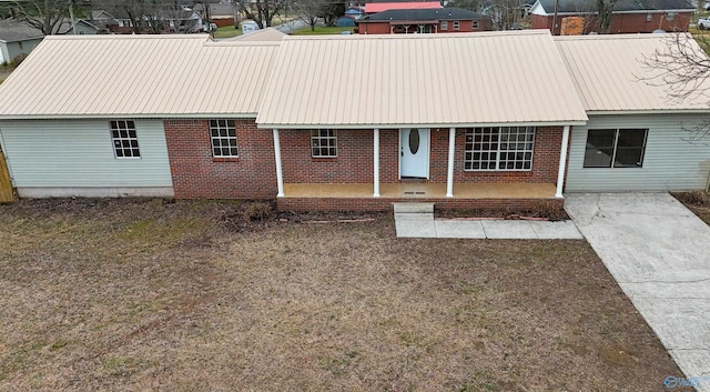 view of front of property featuring brick siding, a porch, and metal roof
