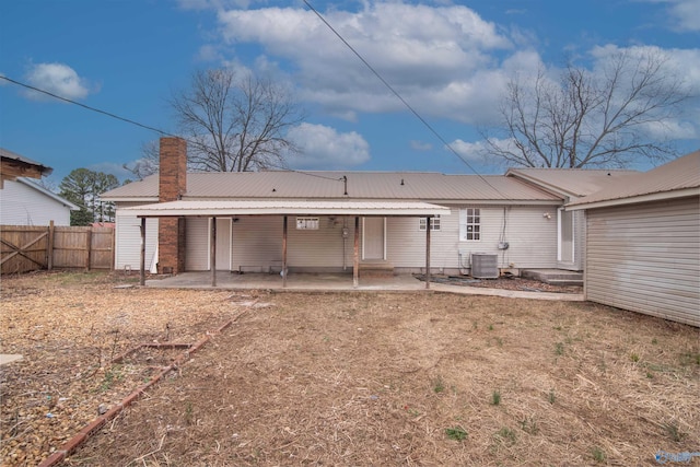rear view of property featuring metal roof, central air condition unit, fence, a chimney, and a patio area
