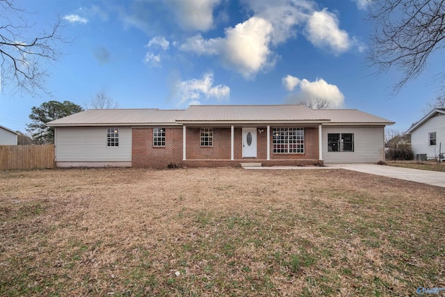 single story home with metal roof, fence, brick siding, a front lawn, and covered porch