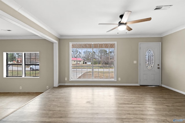 foyer entrance featuring a ceiling fan, a wealth of natural light, crown molding, and visible vents
