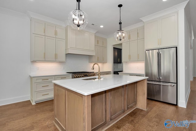 kitchen featuring stainless steel fridge, light stone countertops, a kitchen island with sink, and hardwood / wood-style floors